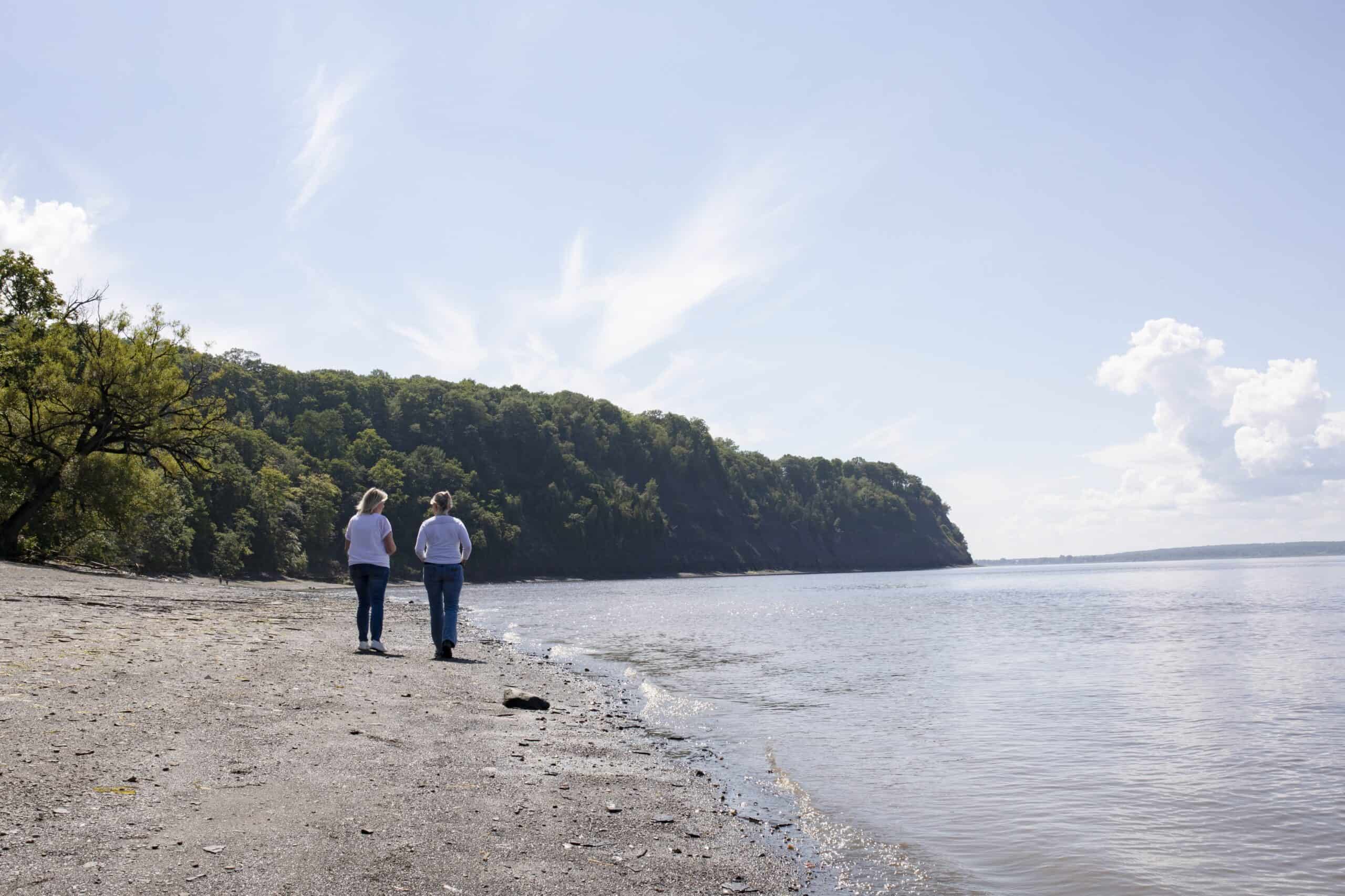 Deux personnes marchent sur la plage ensoleillée.
