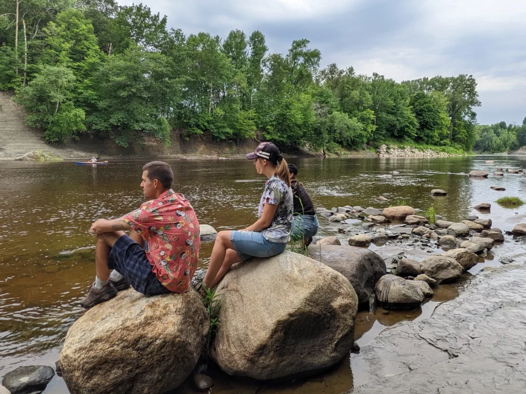 Deux personnes assises sur des rochers près d'une rivière.