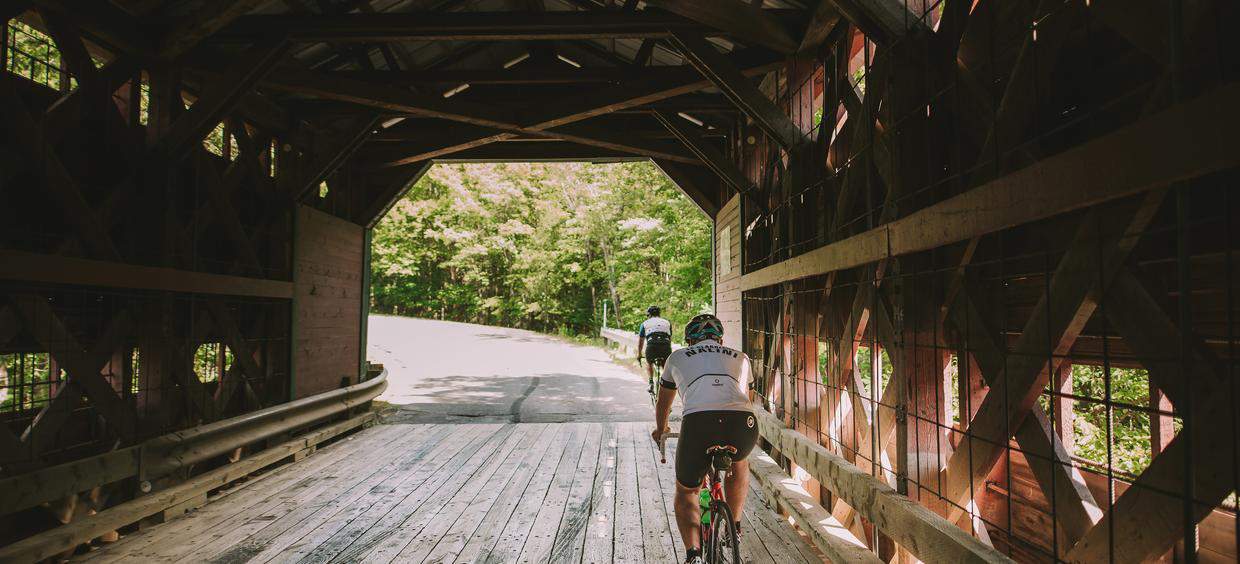 Cyclistes traversant un pont couvert en bois.