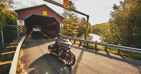 Motard traversant un pont couvert en bois