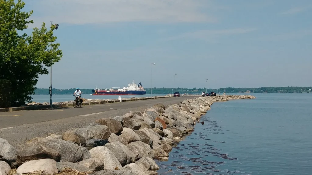 Route côtière avec cycliste et navire en arrière-plan.