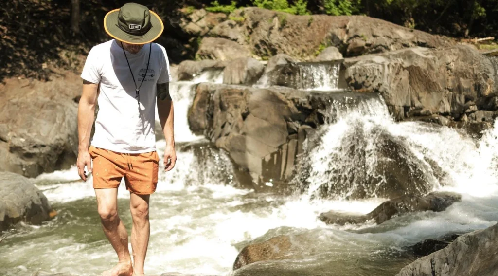 Homme marchant près d'une cascade rocheuse