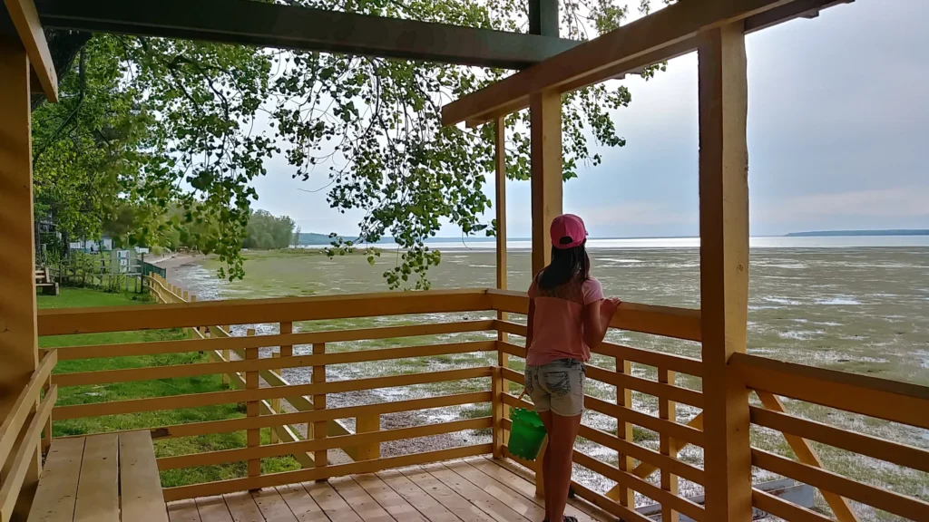Fille observant la plage depuis une terrasse en bois.