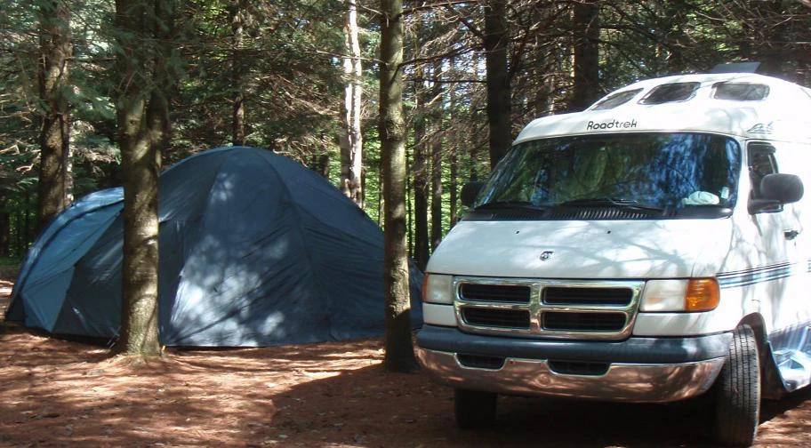 Camping en forêt avec tente et camping-car