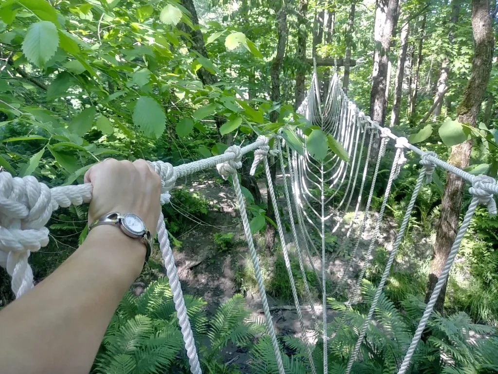 Main tenant une corde sur un pont suspendu.