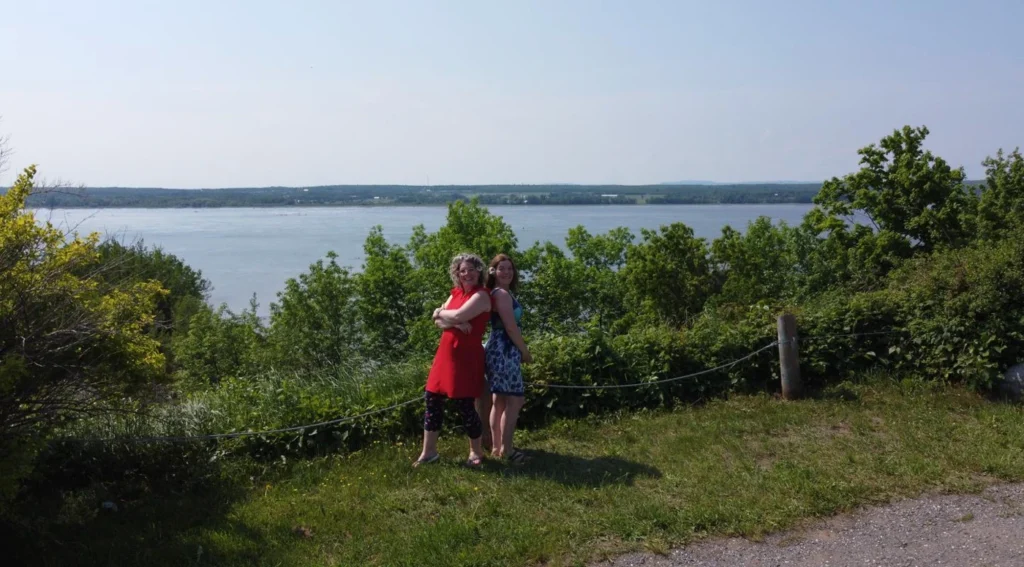Deux femmes devant un paysage de lac et arbres.