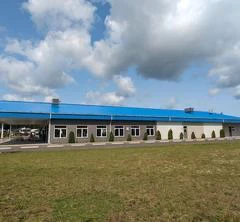 Bâtiment industriel avec toit bleu sous ciel nuageux.