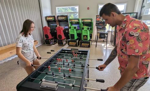 Deux personnes jouent au baby-foot en salle d'arcade.