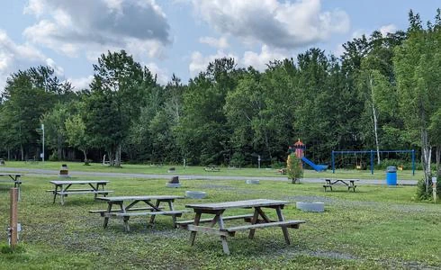 Aire de pique-nique avec tables et jeux pour enfants.