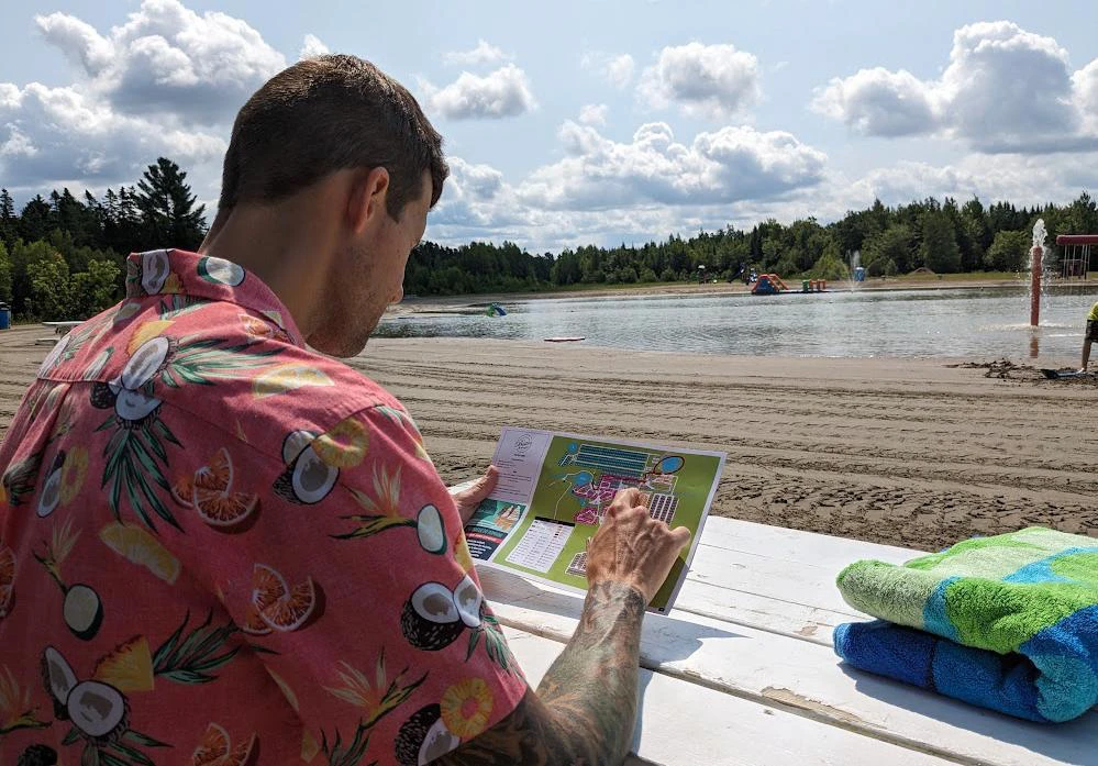 Homme lisant à la plage, chemise colorée.