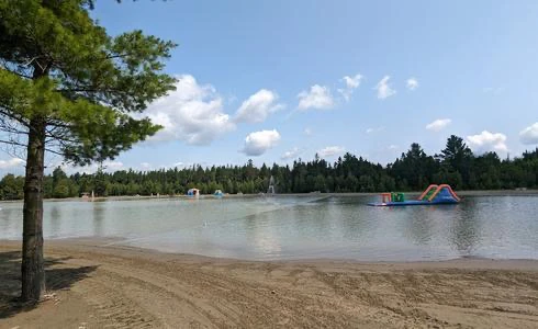 Plage avec jeux gonflables sur l'eau, forêt alentour.
