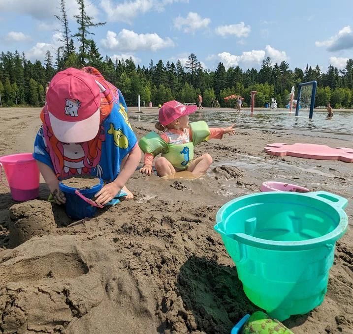 Enfants jouant sur la plage avec des seaux.
