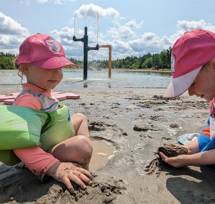 Enfants jouant dans le sable près d'une fontaine.