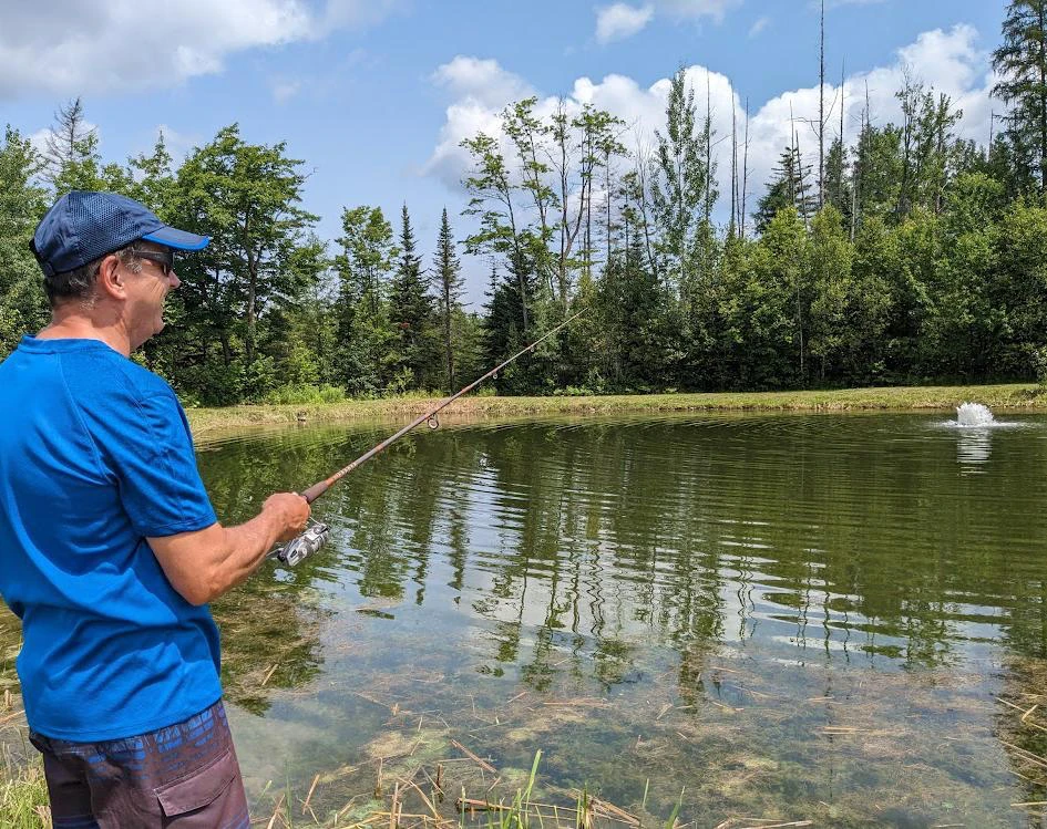 Homme pêchant au bord d'un étang paisible.