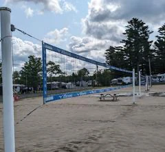 Terrain de volleyball sur sable avec filet.