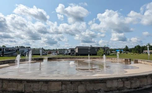 Fontaine circulaire devant camping sous ciel nuageux.