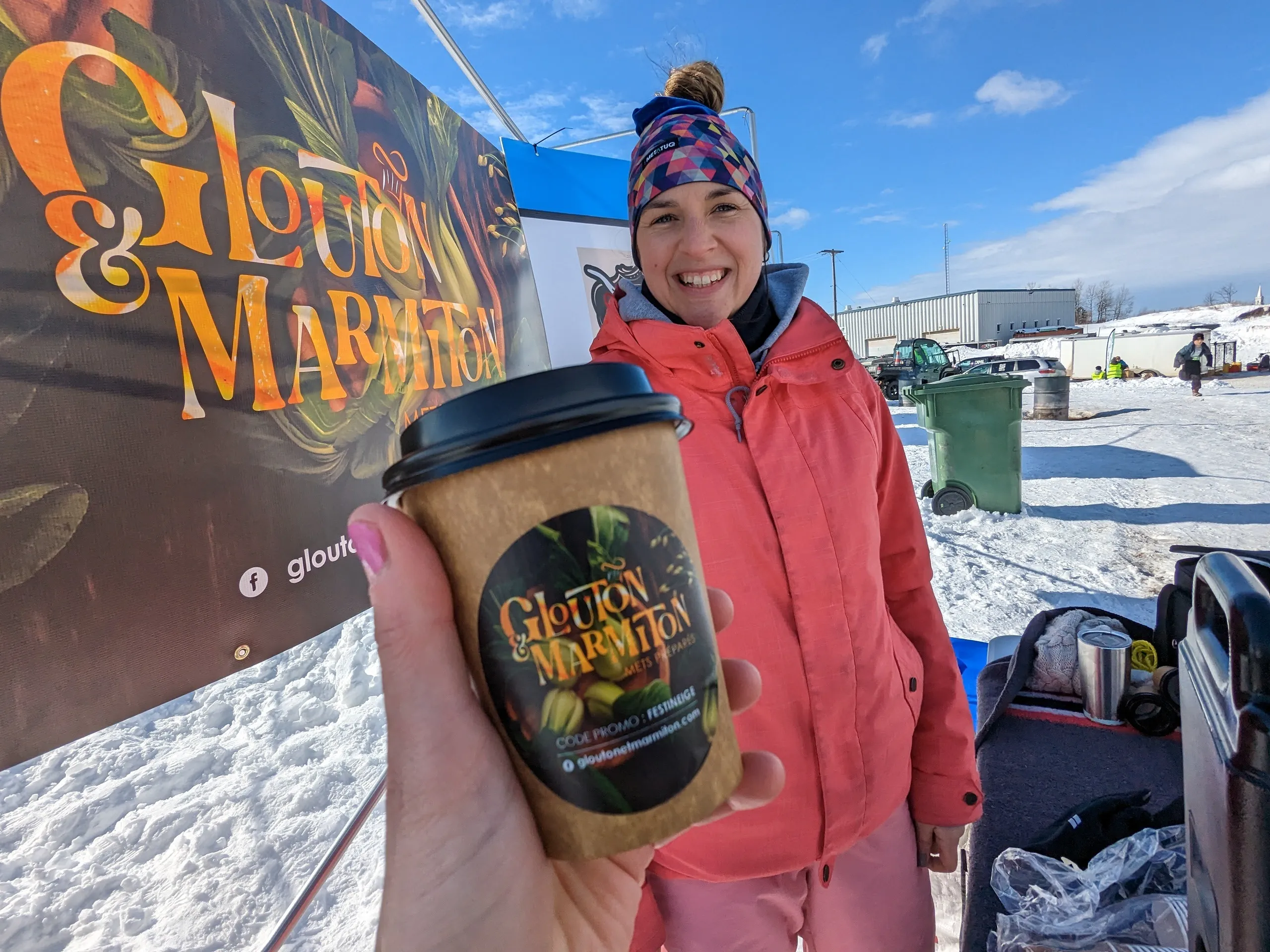 Personne souriante tenant un café lors d'un événement.
