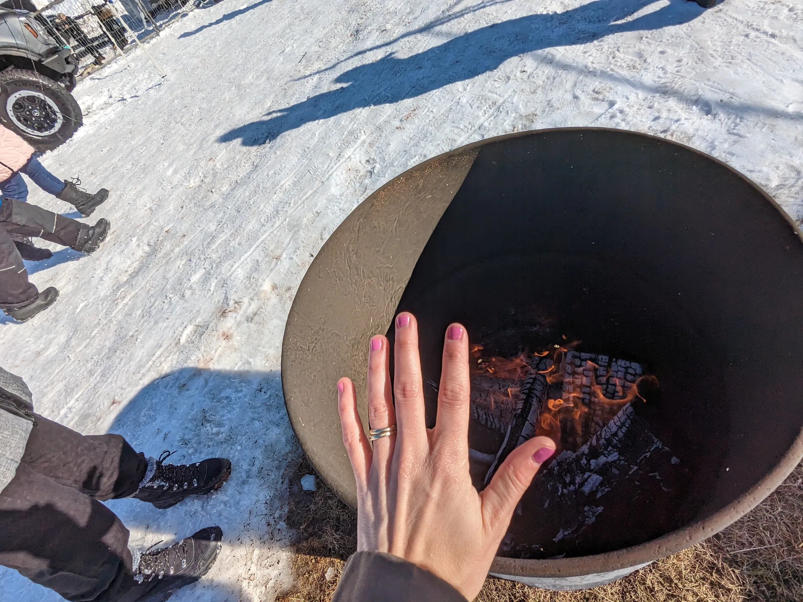 Main se réchauffant près du feu en extérieur.