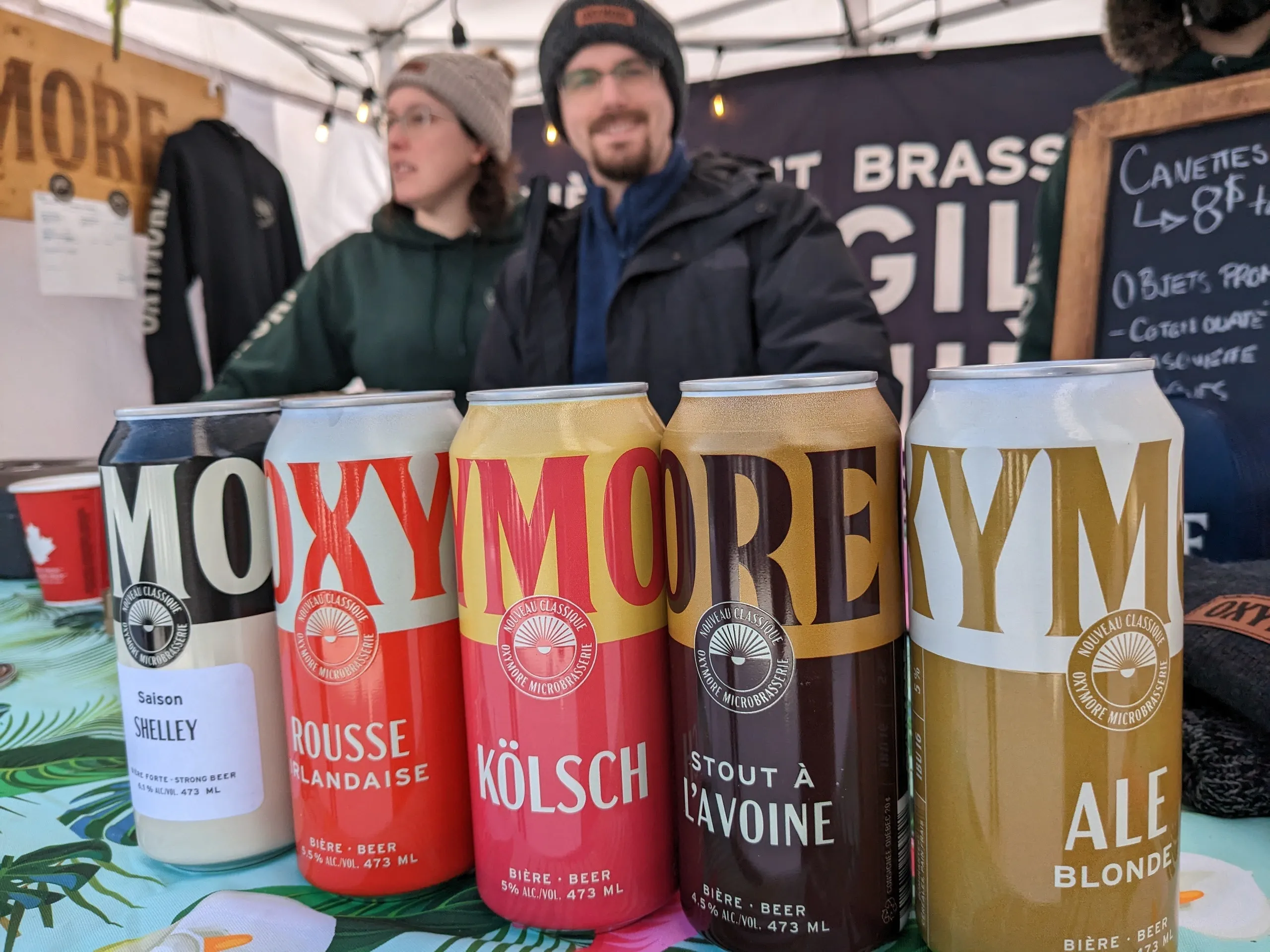 Cinq canettes de bière artisanale sur une table.