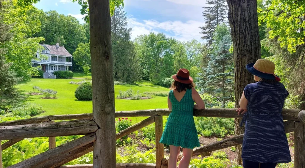 Deux femmes admirent un jardin devant une maison.