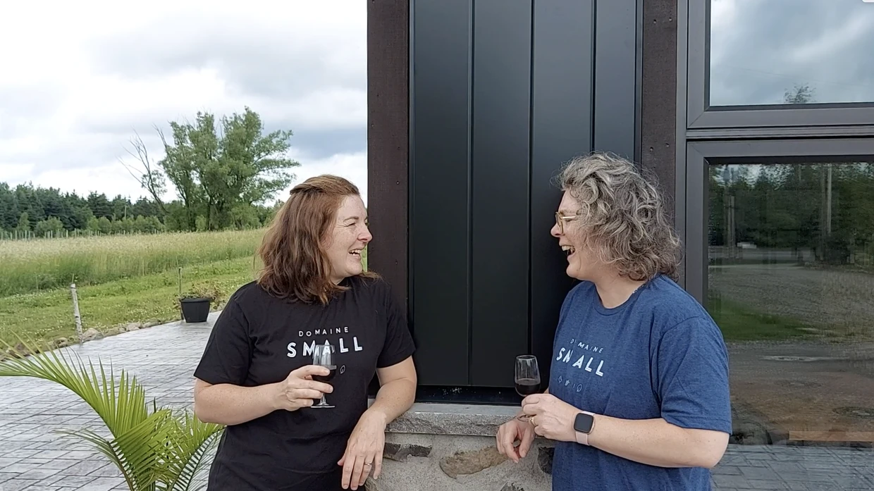 Deux femmes souriantes avec des verres de vin.