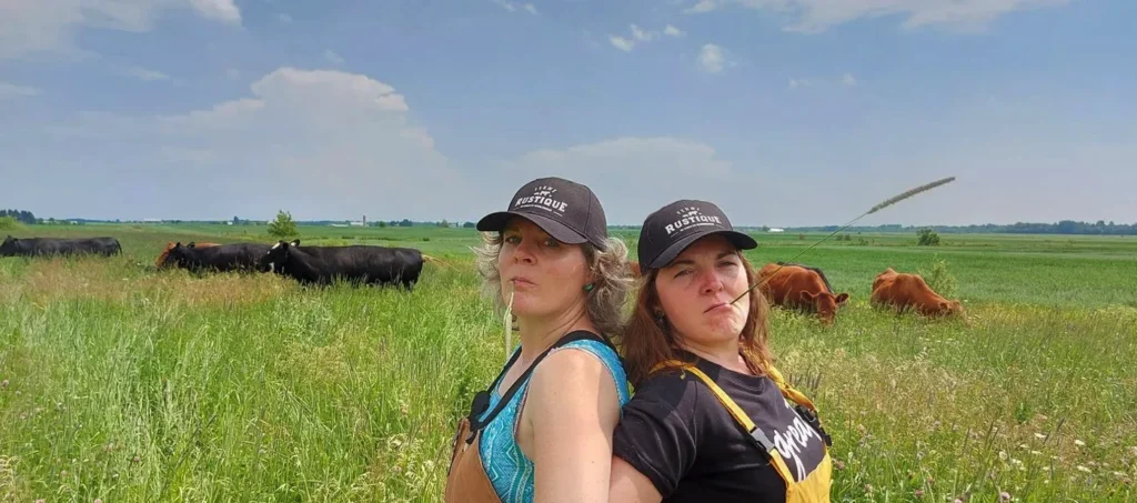 Deux personnes devant des vaches dans un pré.