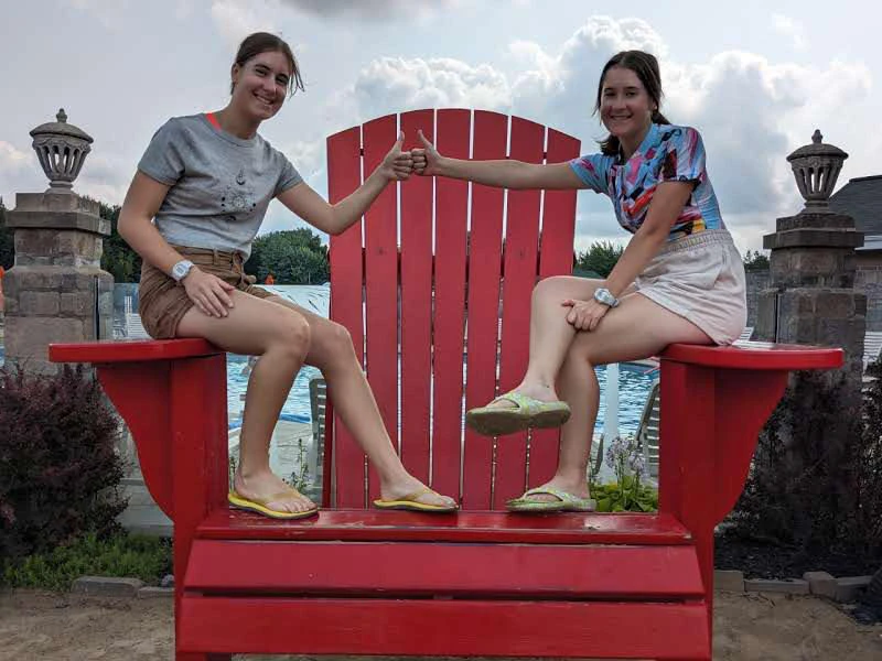 Deux femmes sur une grande chaise rouge, souriantes.