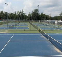 Terrains de tennis extérieurs vides sous ciel nuageux.