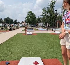 Joueurs lancent sacs sur terrain de cornhole extérieur.