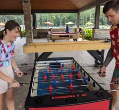 Deux personnes jouant au baby-foot sous un abri.