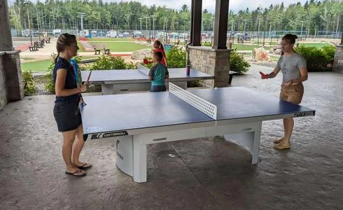 Personnes jouent au tennis de table en extérieur.