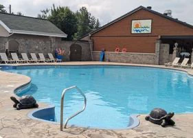 Piscine extérieure avec chaises longues et fontaine décorative.