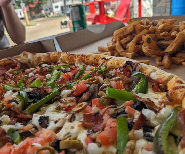 Pizza garnie avec frites sur une table.