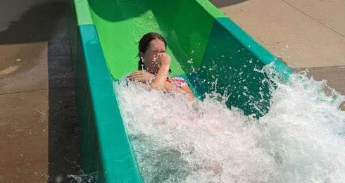 Personne descendant un toboggan aquatique, éclaboussures d'eau.