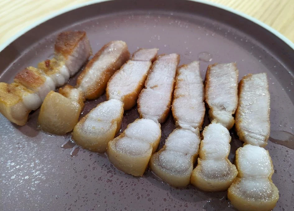 Tranches de lard grillées sur une assiette marron.