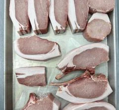 Tranches de viande de porc sur plateau métallique.