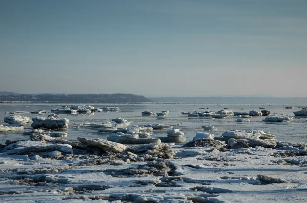 Paysage hivernal avec glace flottante sur lac.
