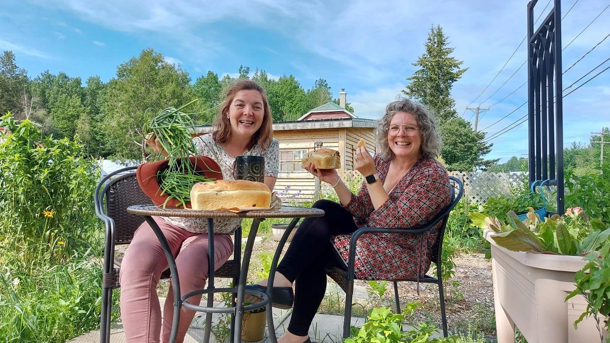 Deux femmes partageant un repas dans un jardin.