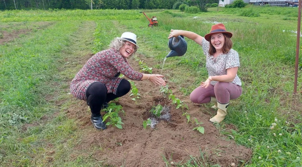 Deux femmes arrosent des plants dans un jardin