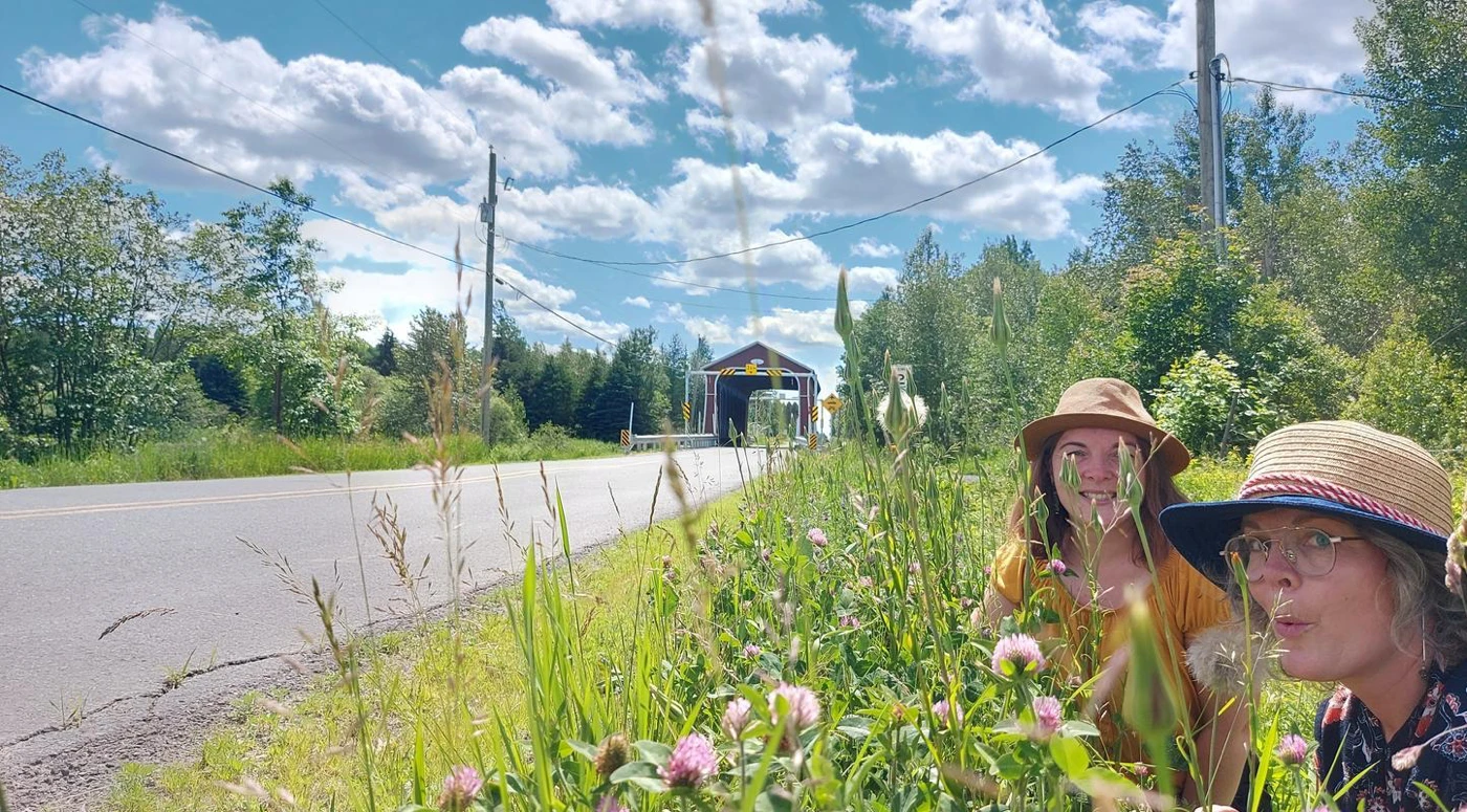 Deux femmes souriantes devant un pont couvert.