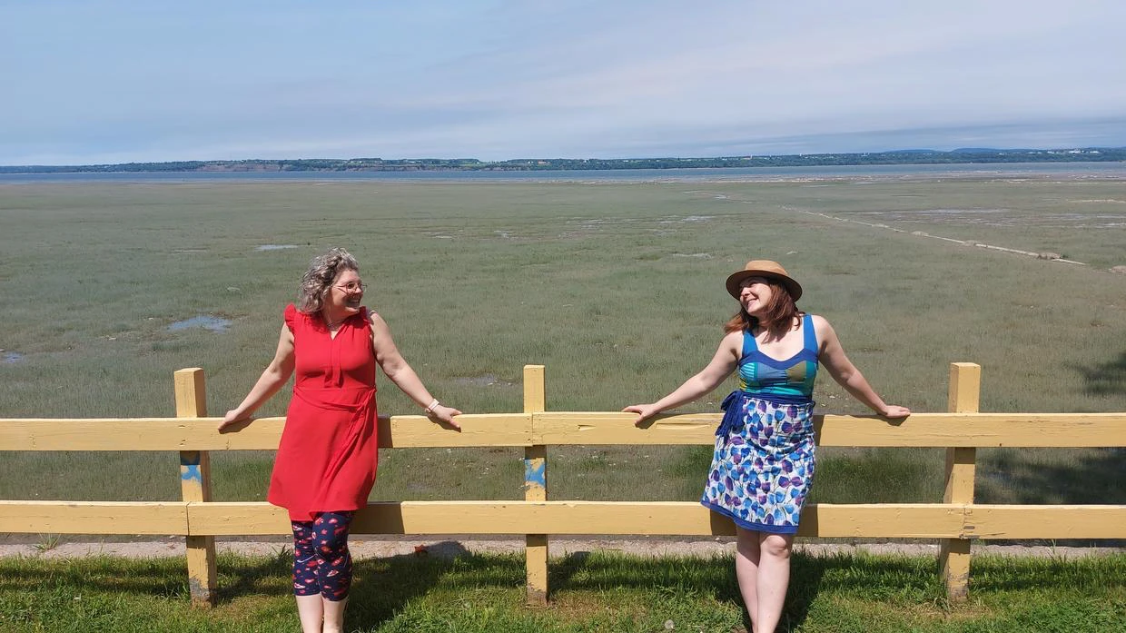 Deux femmes devant un paysage de prairie.