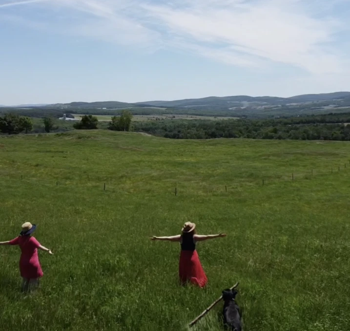 Deux femmes dans champs verts avec chien.