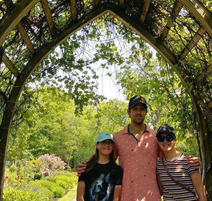 Personnes sous une arche dans un jardin fleuri.