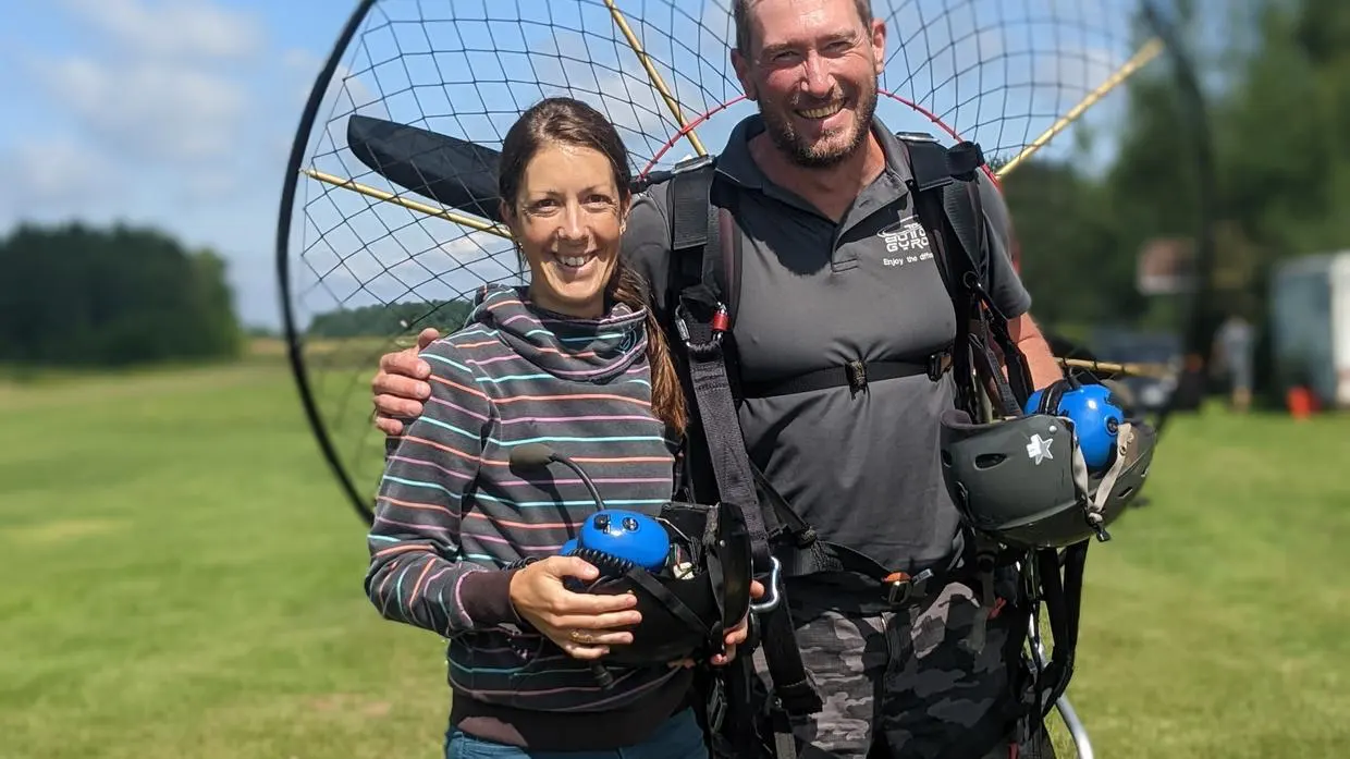 Couple souriant avec équipement de parapente en plein air.