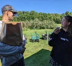 Deux personnes souriantes dans un verger verdoyant.