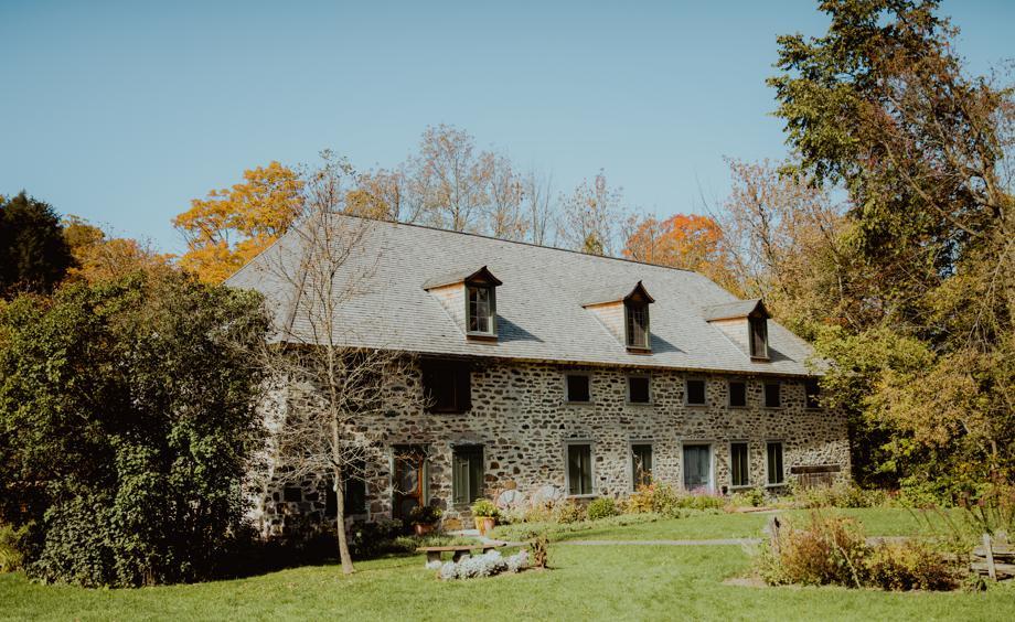 Maison en pierre entourée d'arbres en automne.