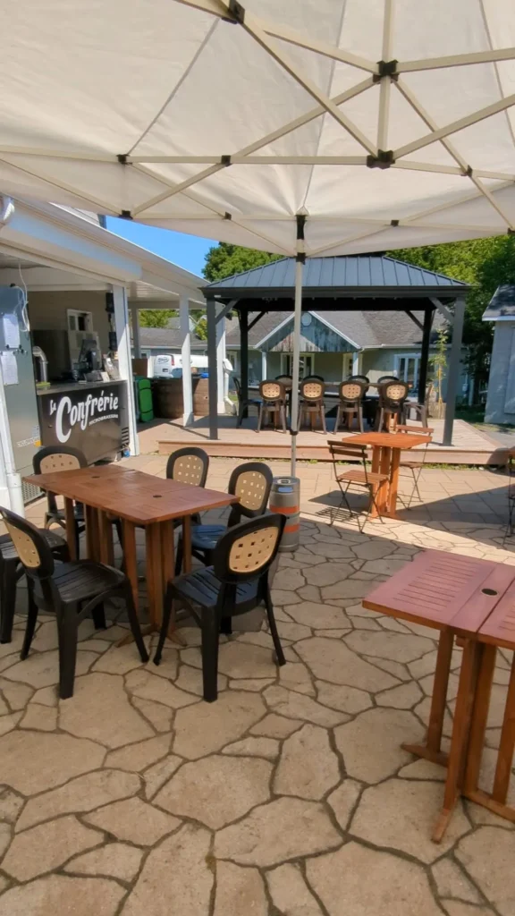 Terrasse extérieure avec tables et chaises sous tonnelle.