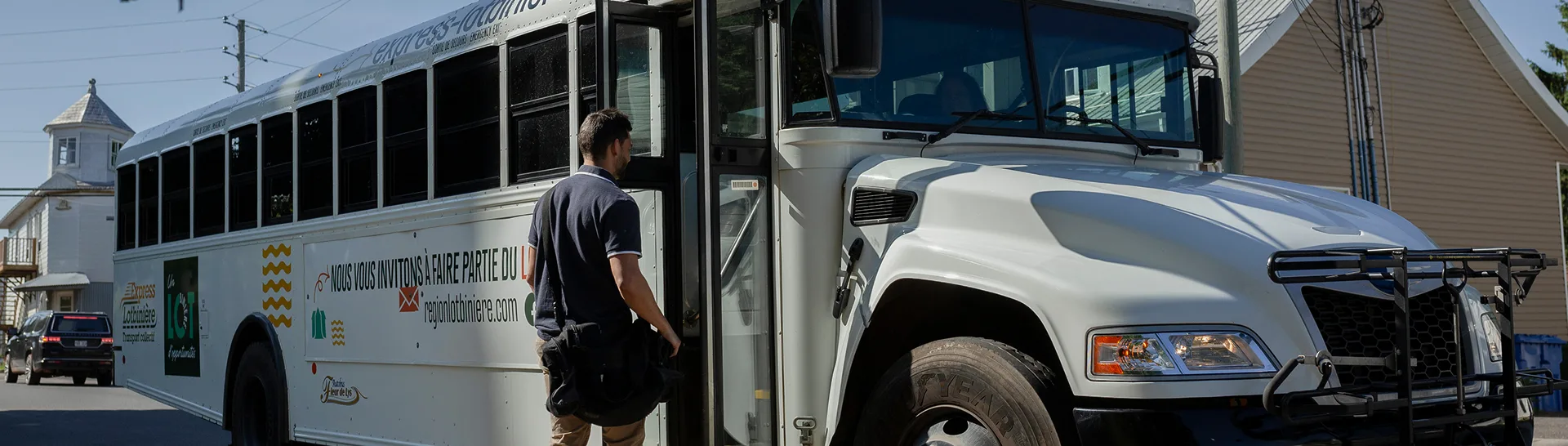 Homme montant dans un bus blanc en ville.